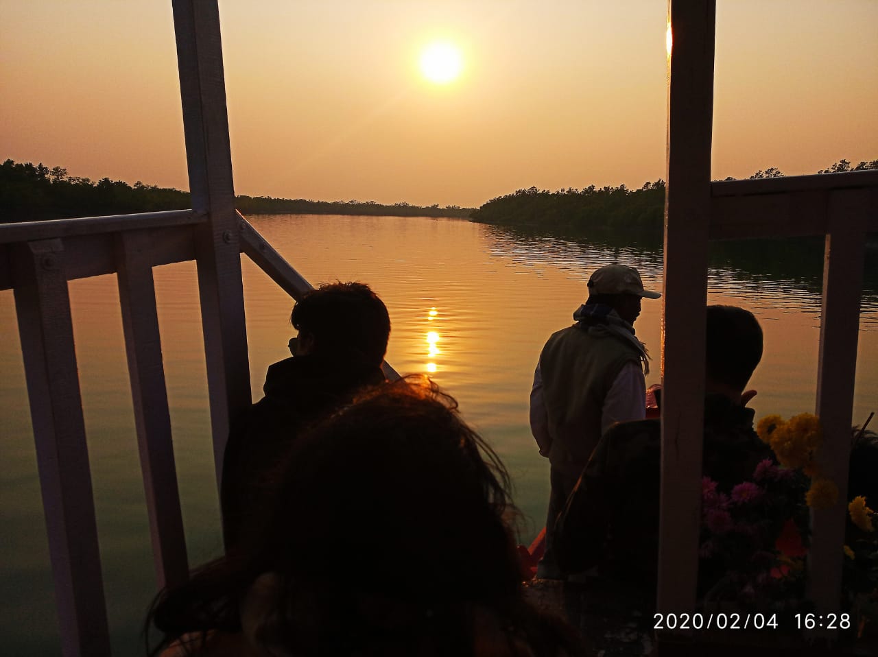 Tourist boat resting near riverbank under colorful sunset sky in Sundarbans